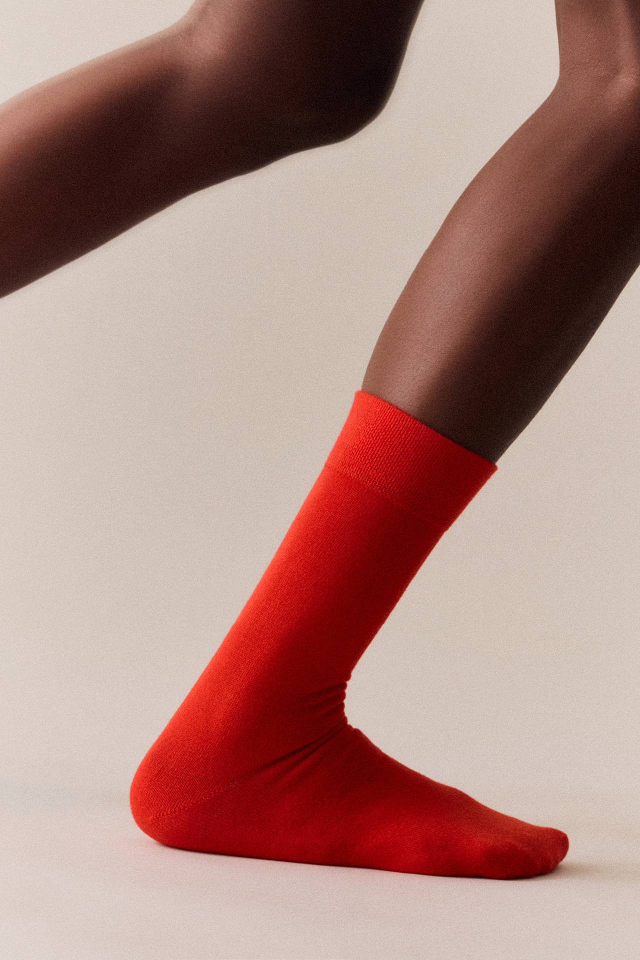 Red sock worn by a person on a beige background