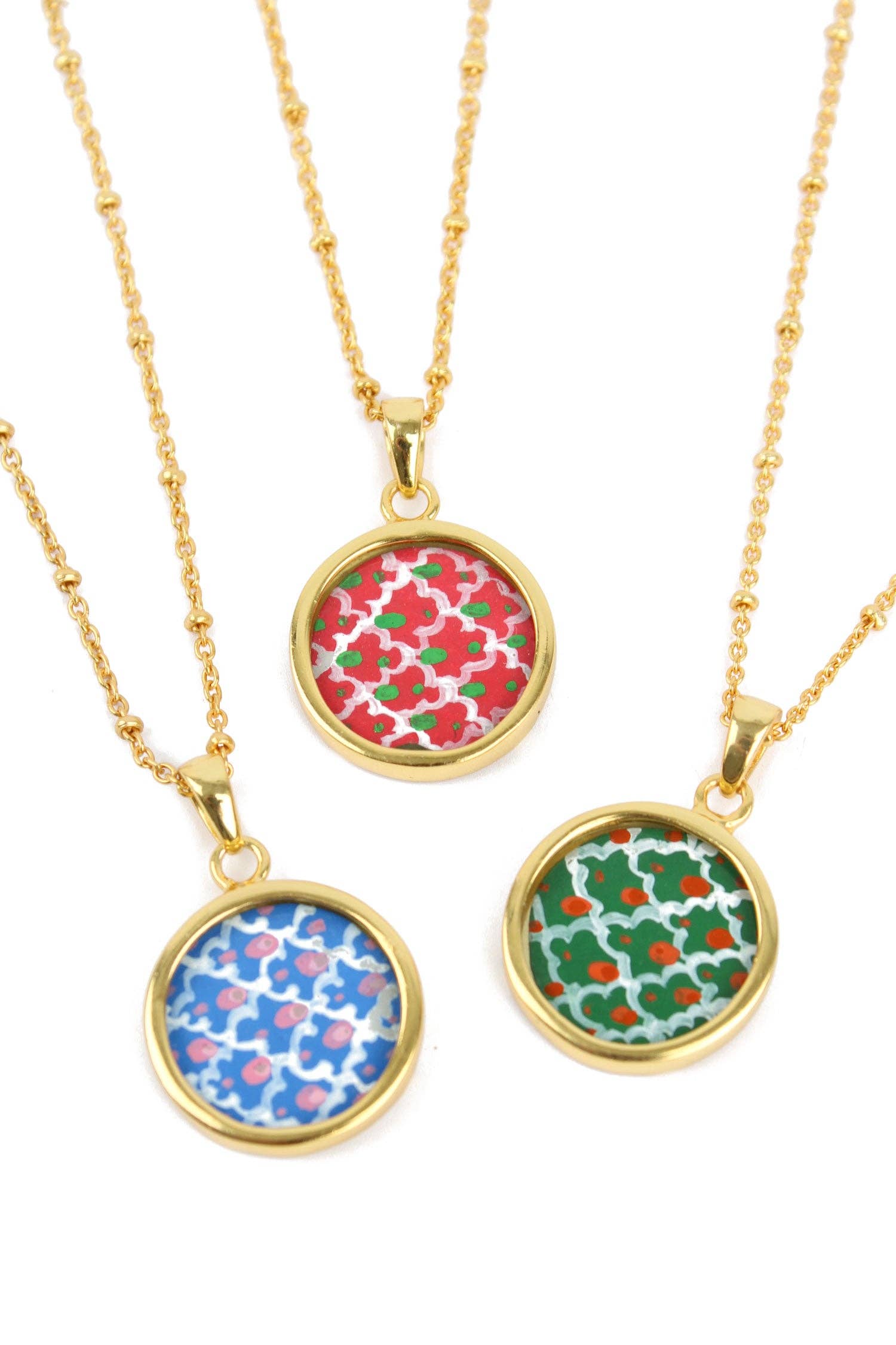 Three gold necklaces with colorful circular pendants on a white background