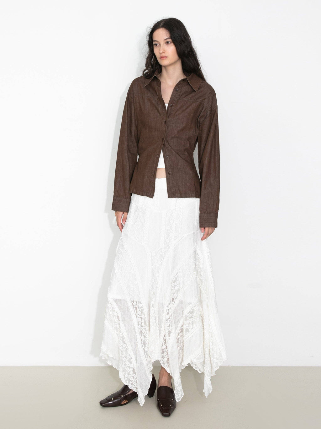 Woman wearing a brown jacket and white lace skirt on a white background