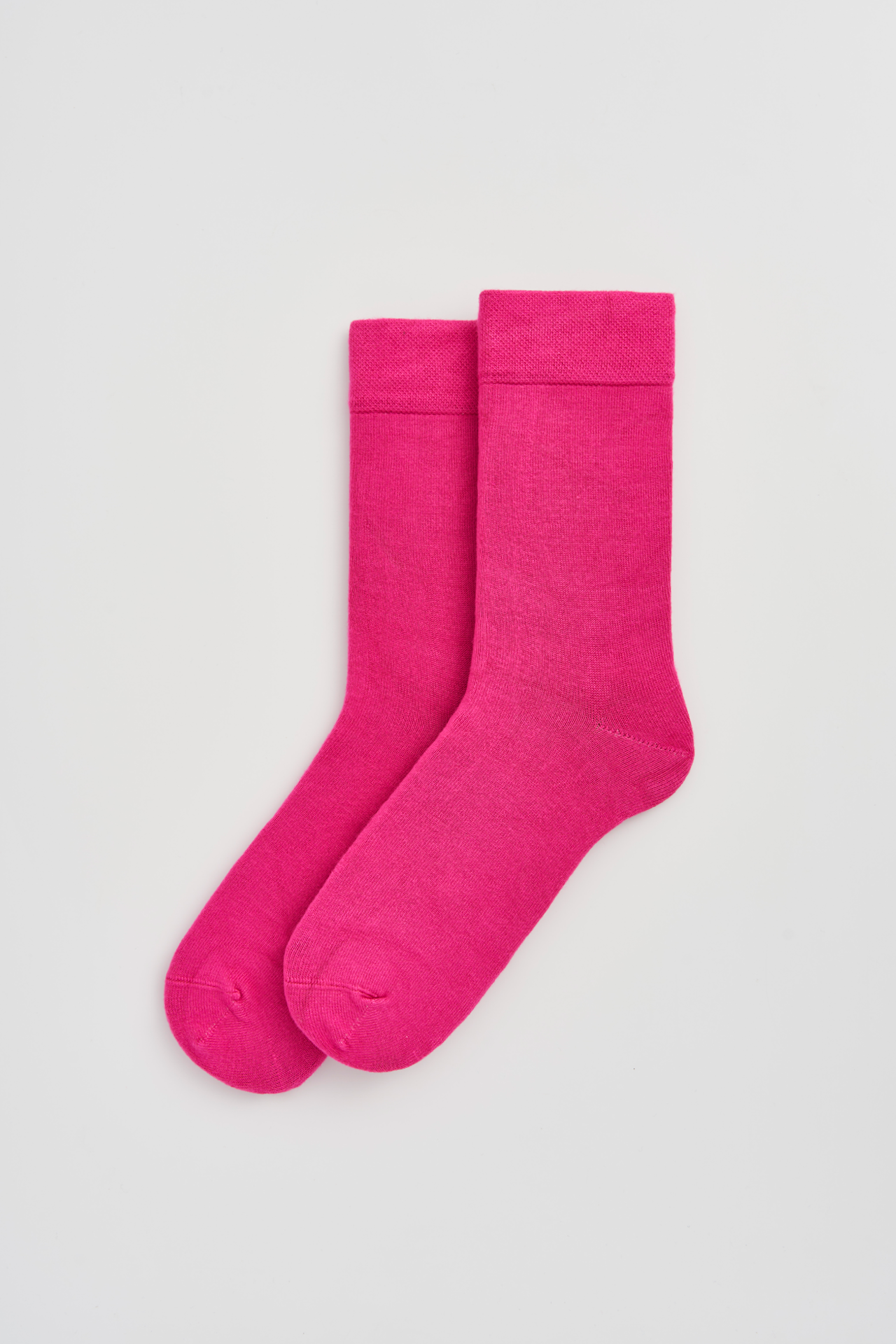 Pair of bright pink socks on a light gray background