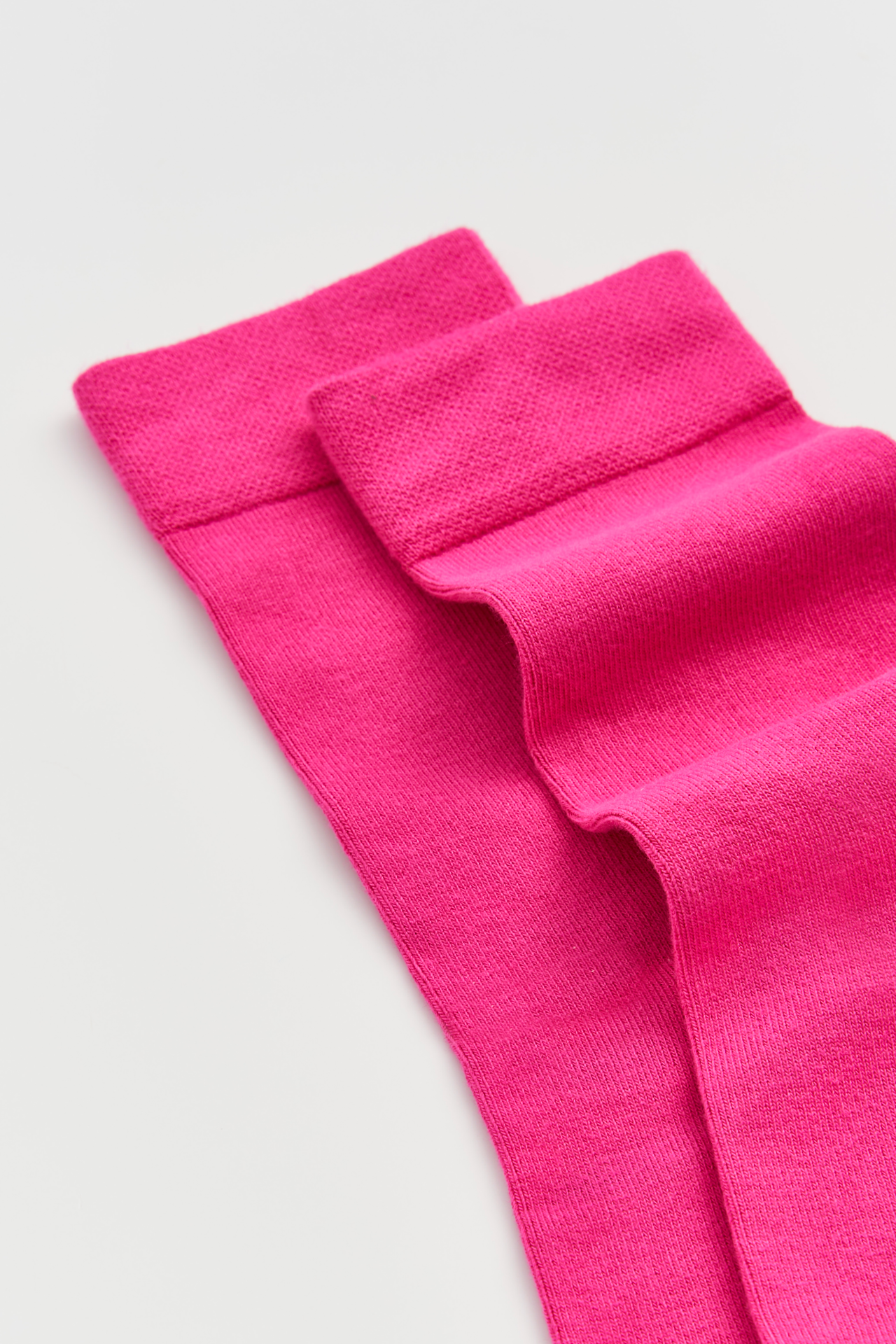 Two bright pink socks on a light gray background