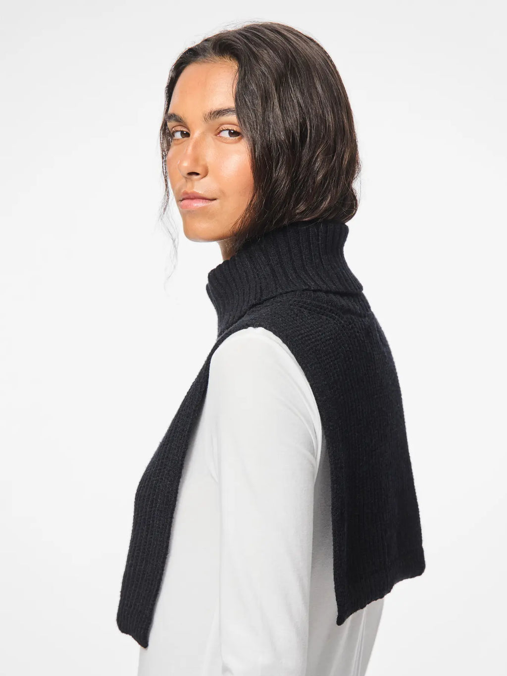 Person wearing a black turtleneck sweater over a white shirt on a white background