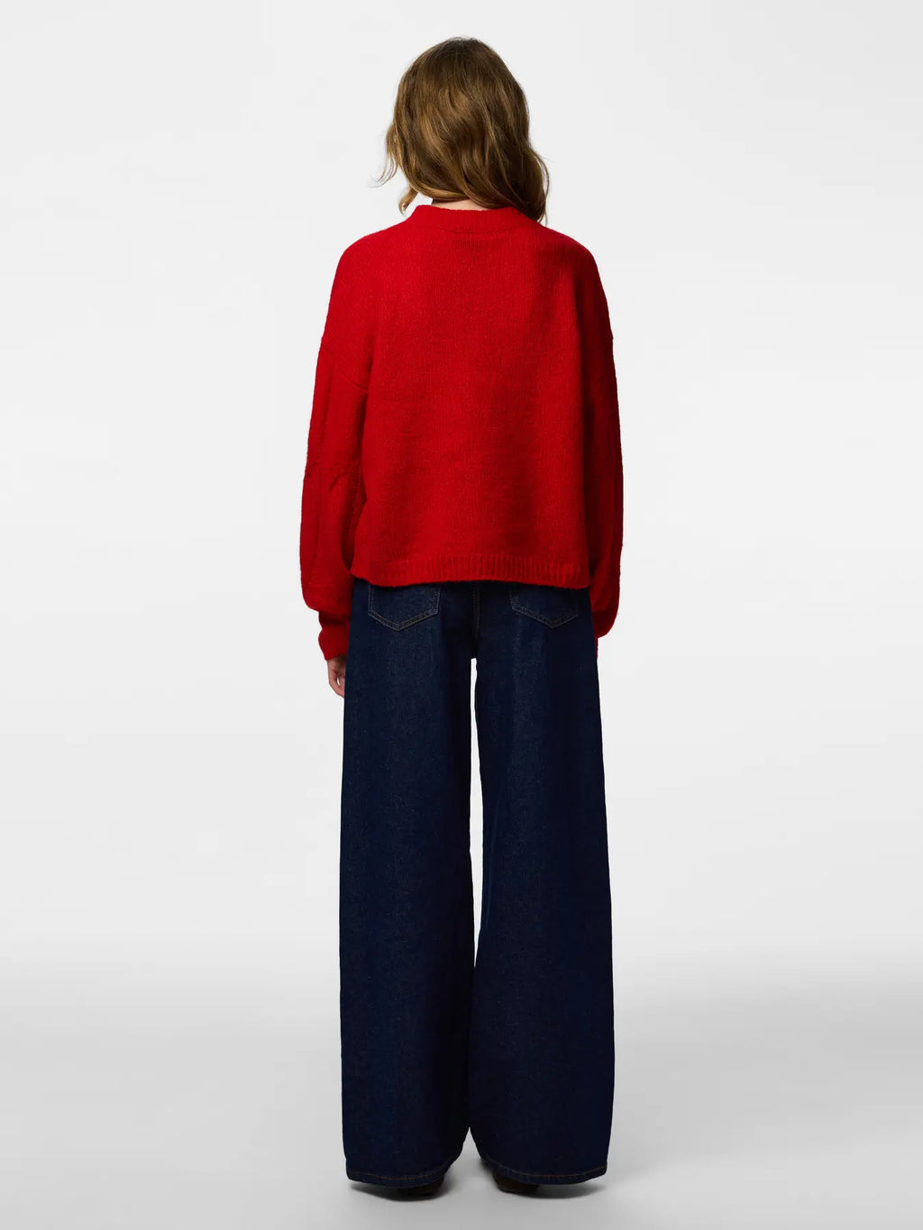 Person wearing a red sweater and dark blue pants on a white background