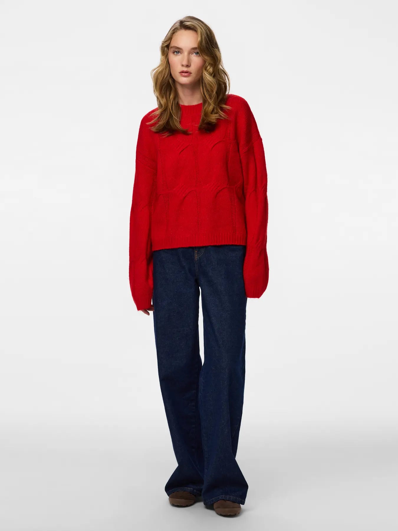 Woman wearing a red sweater and blue jeans on a white background
