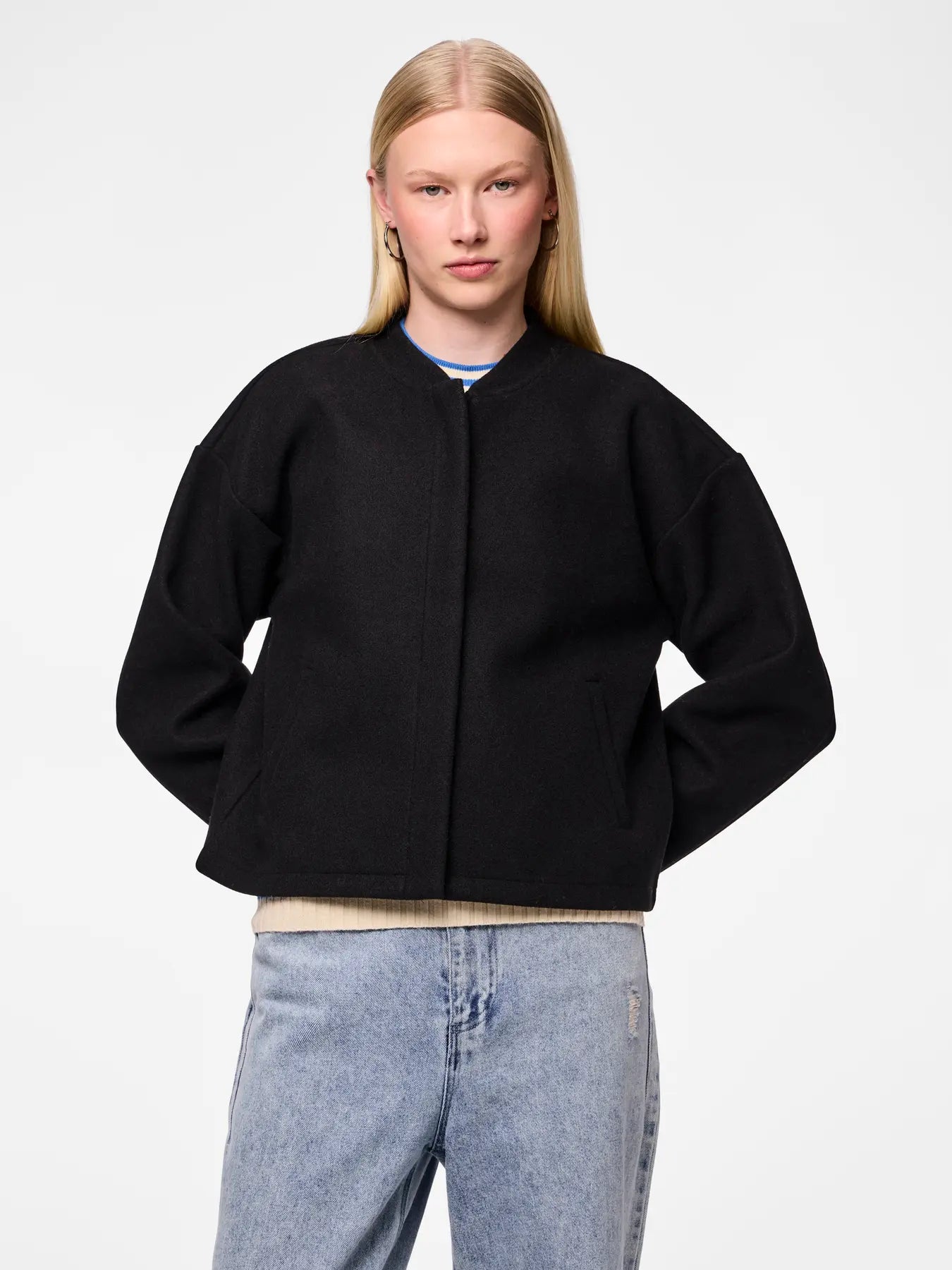 Person wearing a black jacket and light blue jeans on a white background