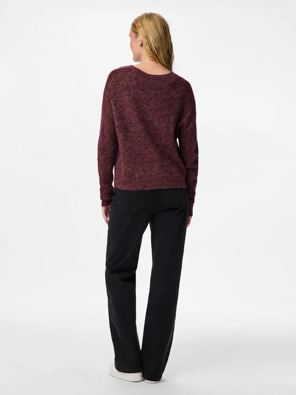 Person wearing a maroon sweater and black pants on a white background