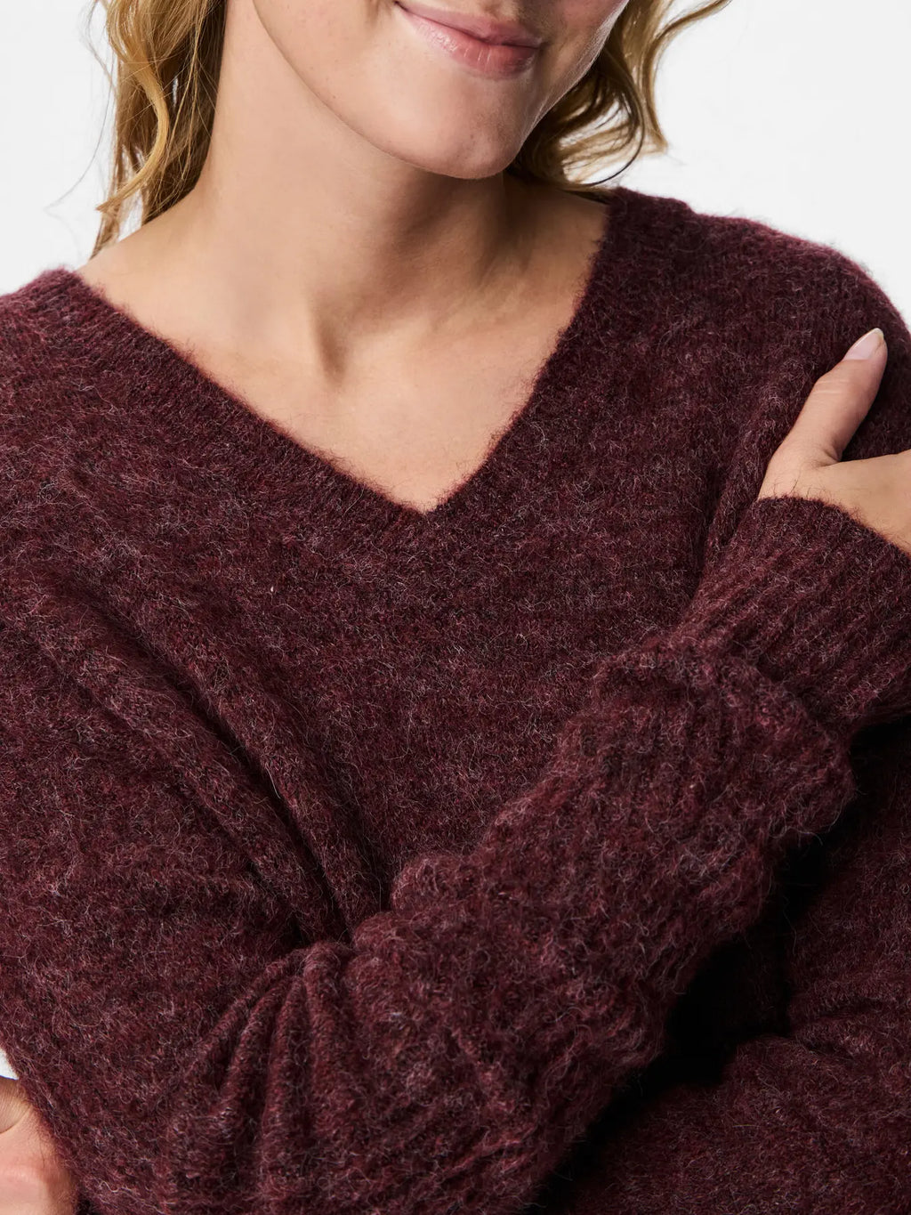 Close-up of a person wearing a dark purple sweater with a blurred background