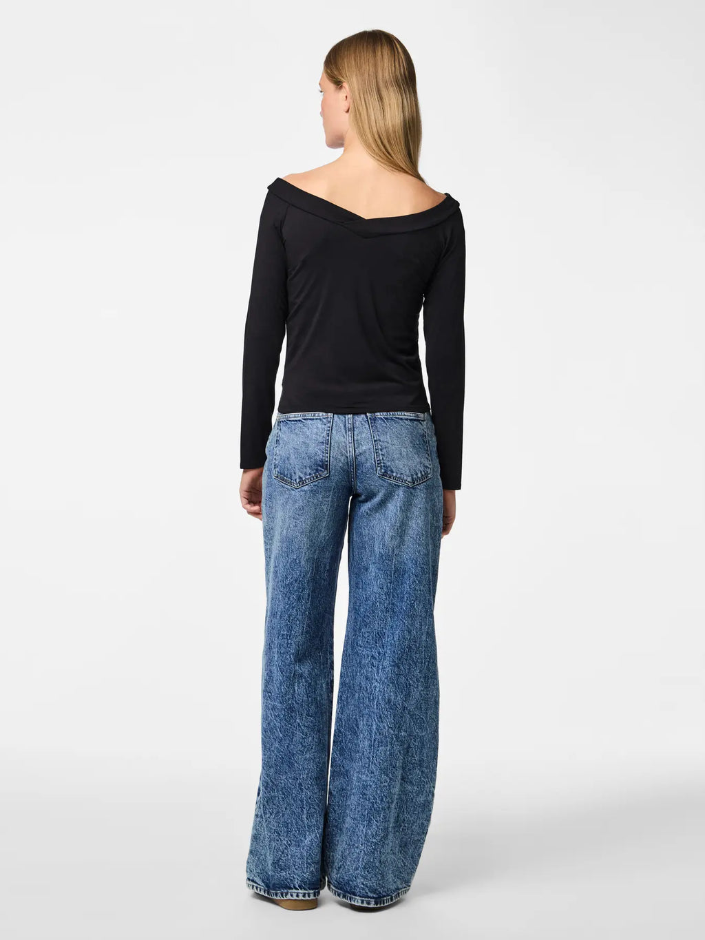 Woman wearing a black top and blue jeans on a white background