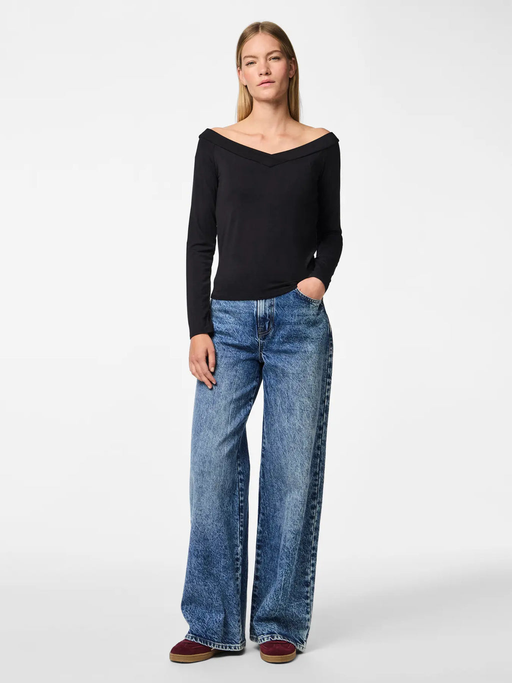 Woman wearing a black top and blue jeans on a white background