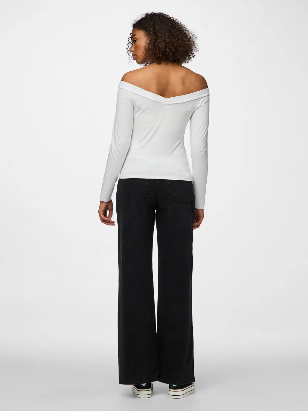 Woman wearing a white off-shoulder top and black pants on a white background