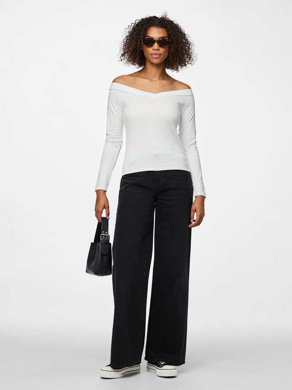 Woman wearing a white off-shoulder top and black pants on a white background