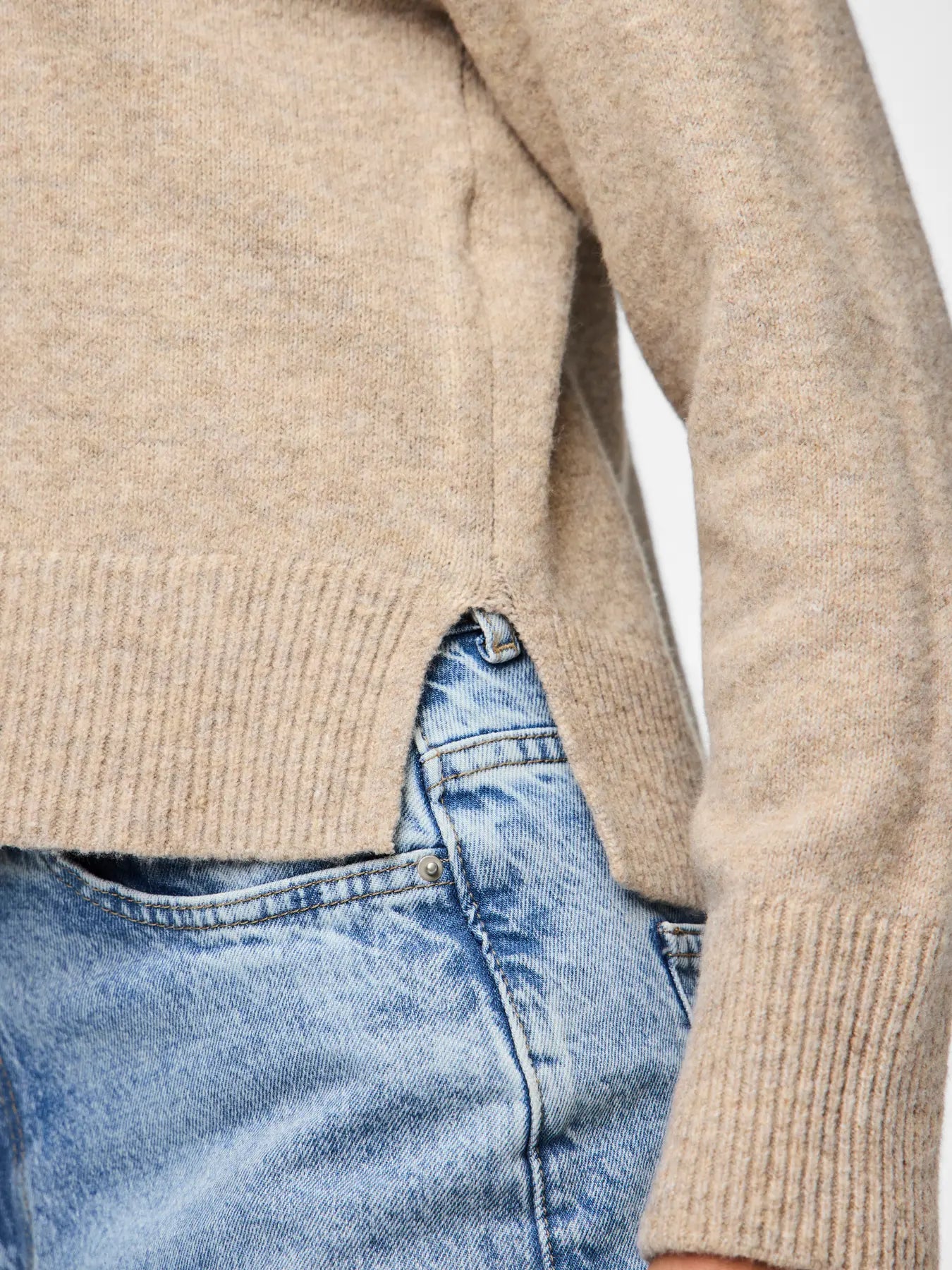 Beige sweater worn by a person with a blurred background