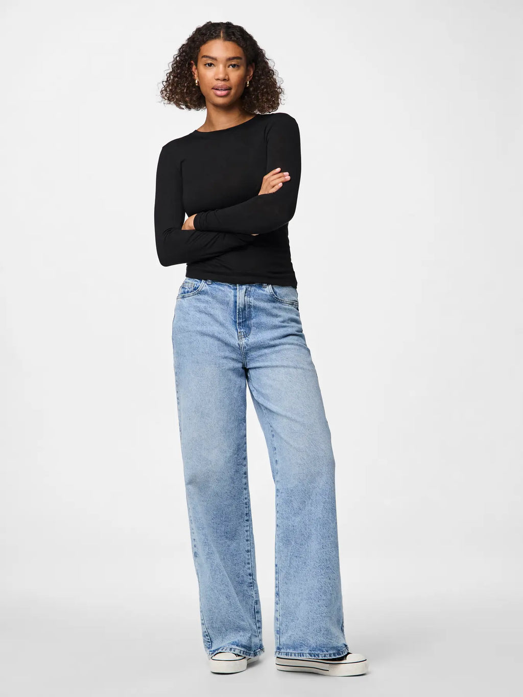 Woman wearing a black top and light blue jeans on a white background