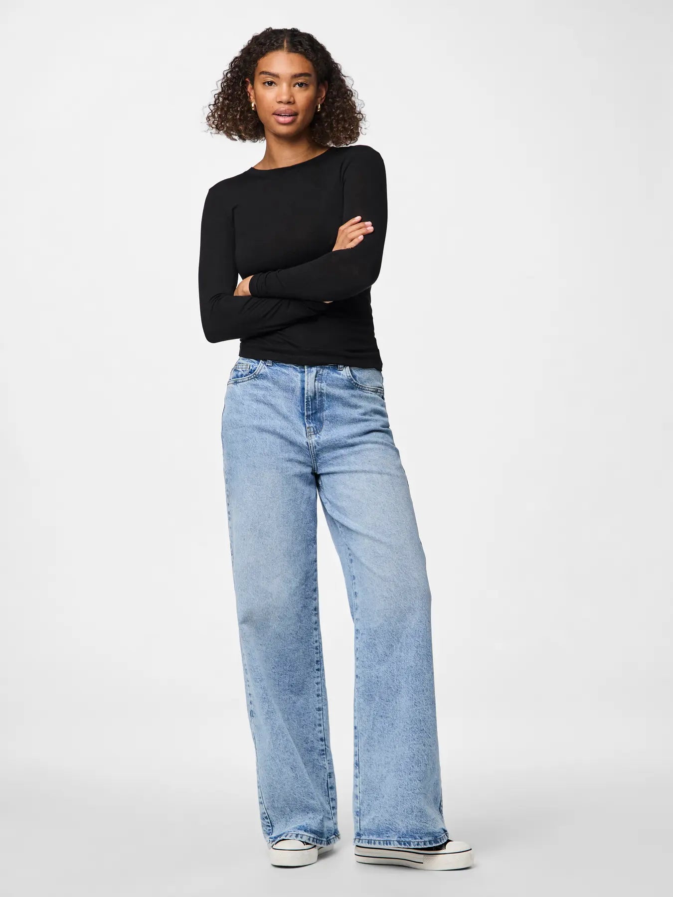 Woman wearing a black top and light blue jeans on a white background