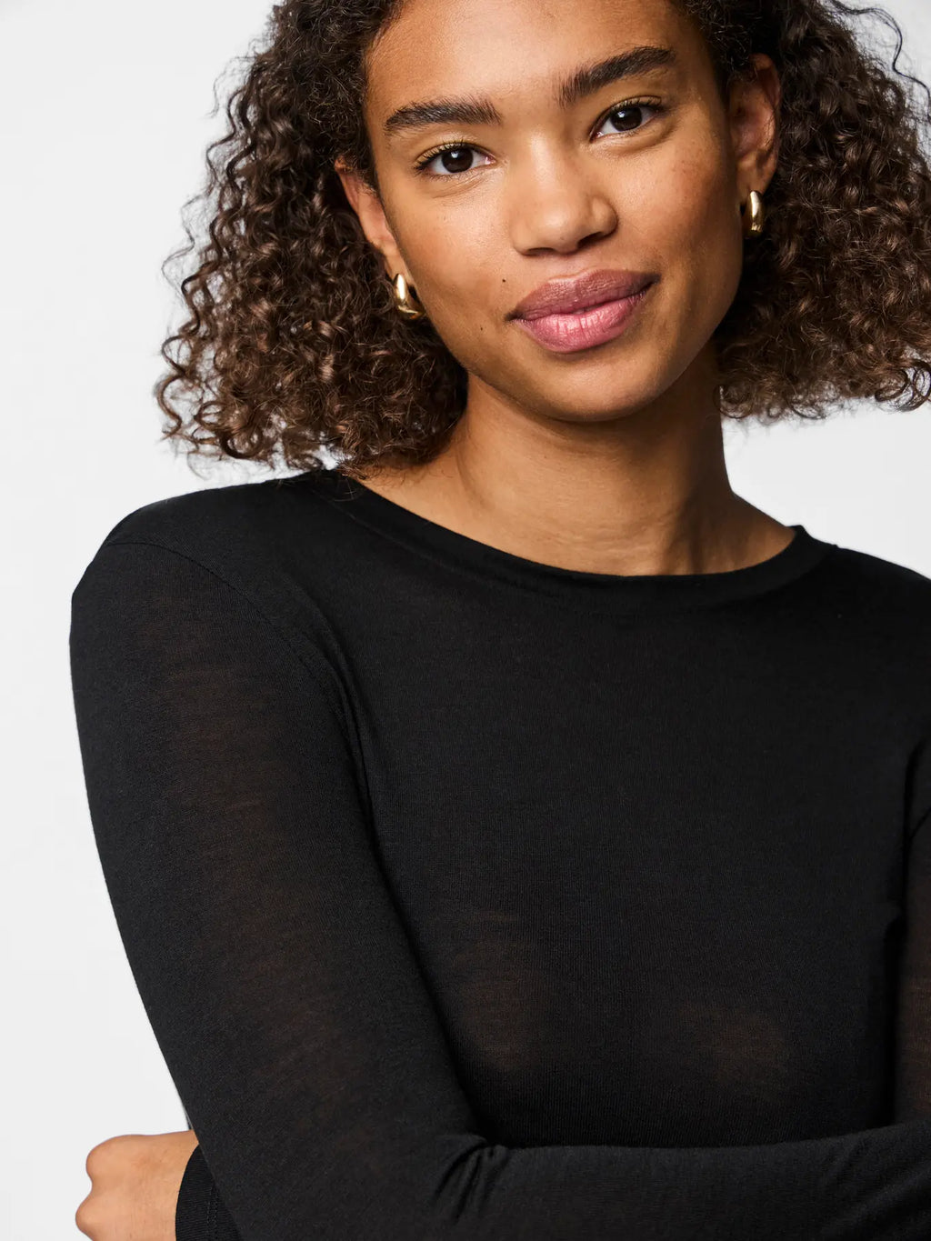 Woman wearing a black long-sleeve top against a plain background