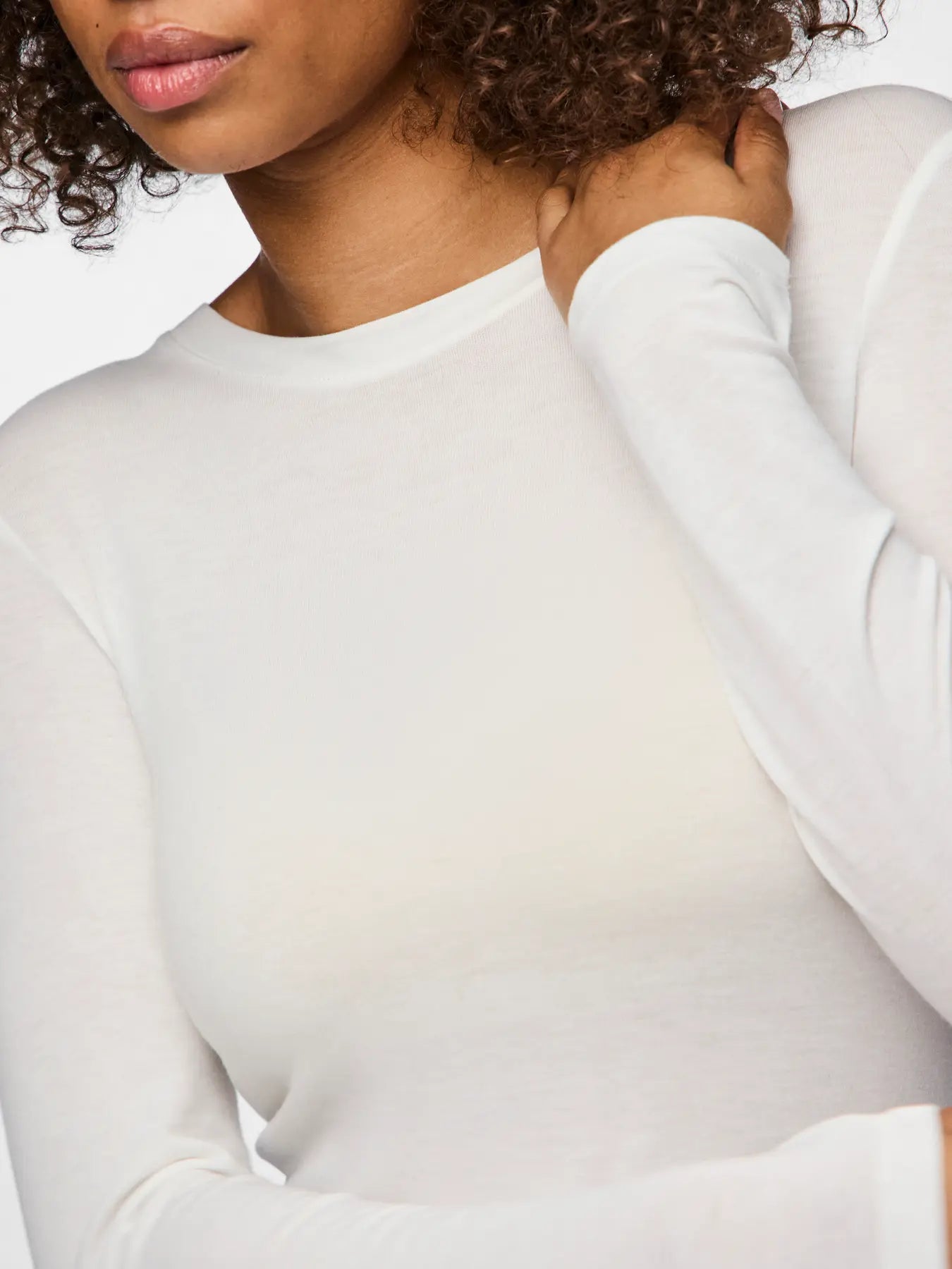 Person wearing a white long-sleeve shirt against a plain background