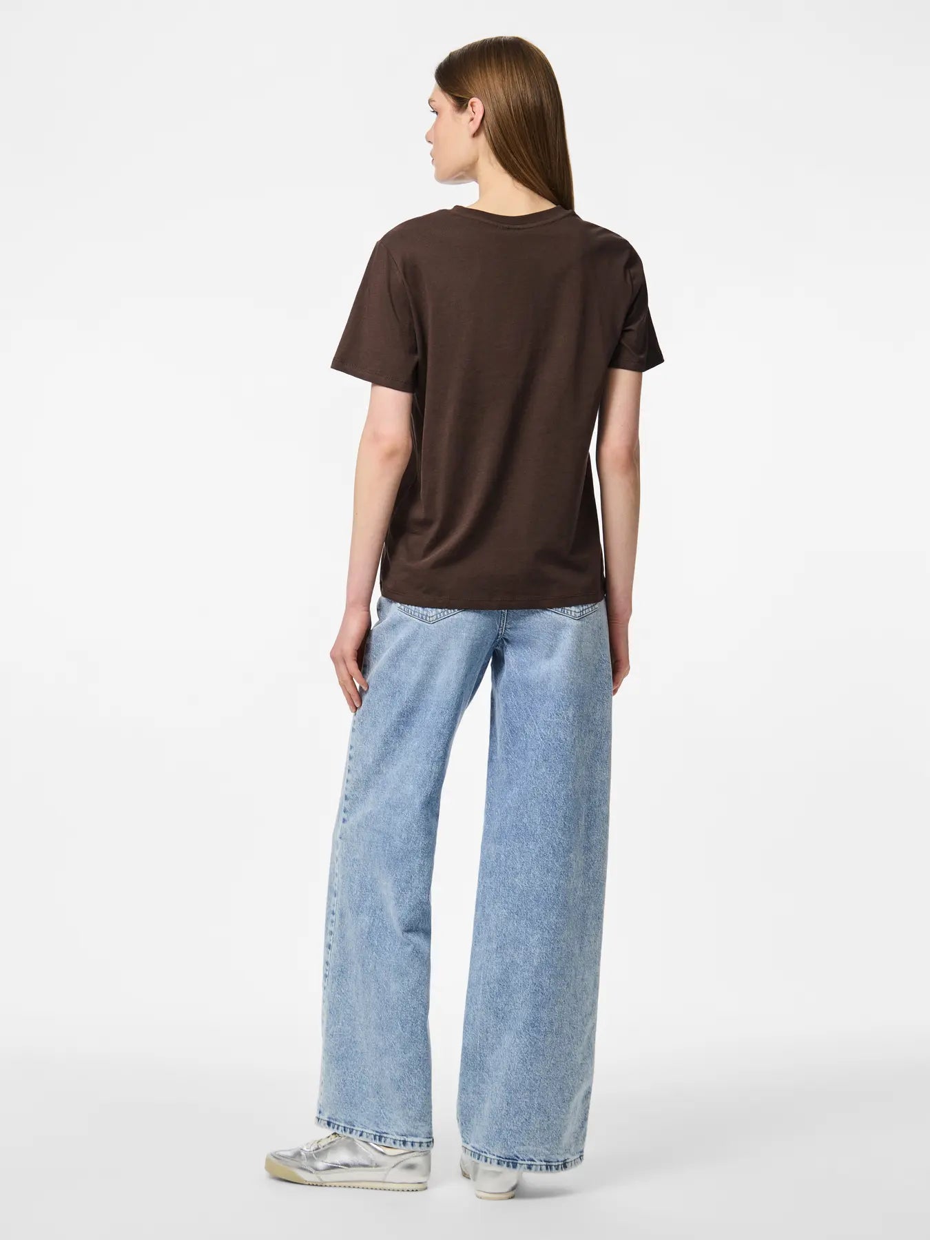 Person wearing a brown t-shirt and light blue jeans on a white background