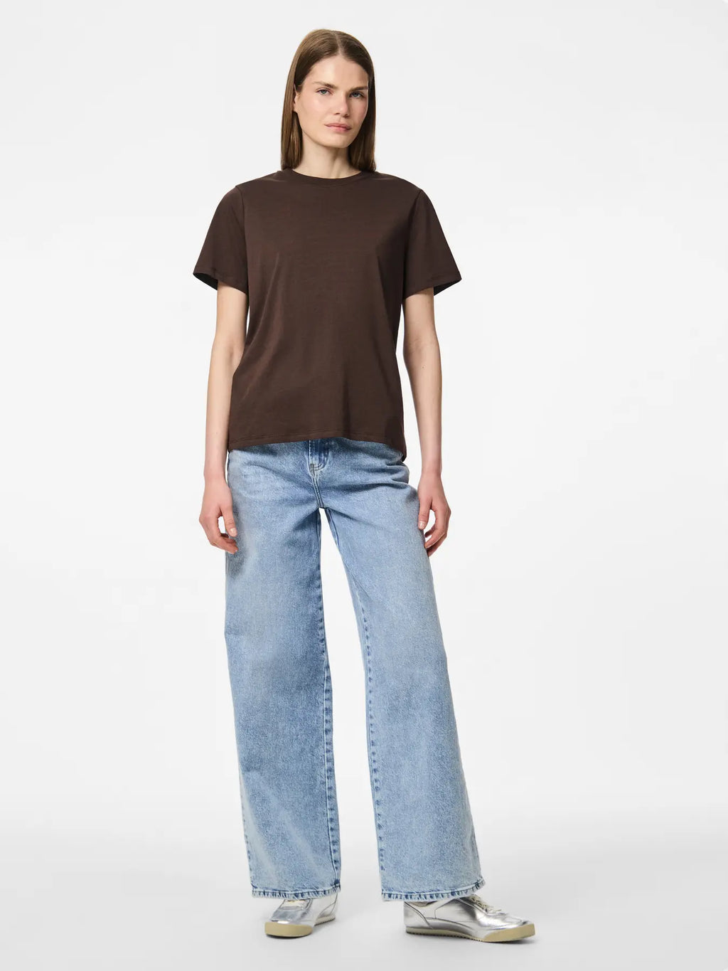 Person wearing a brown t-shirt and light blue jeans on a white background