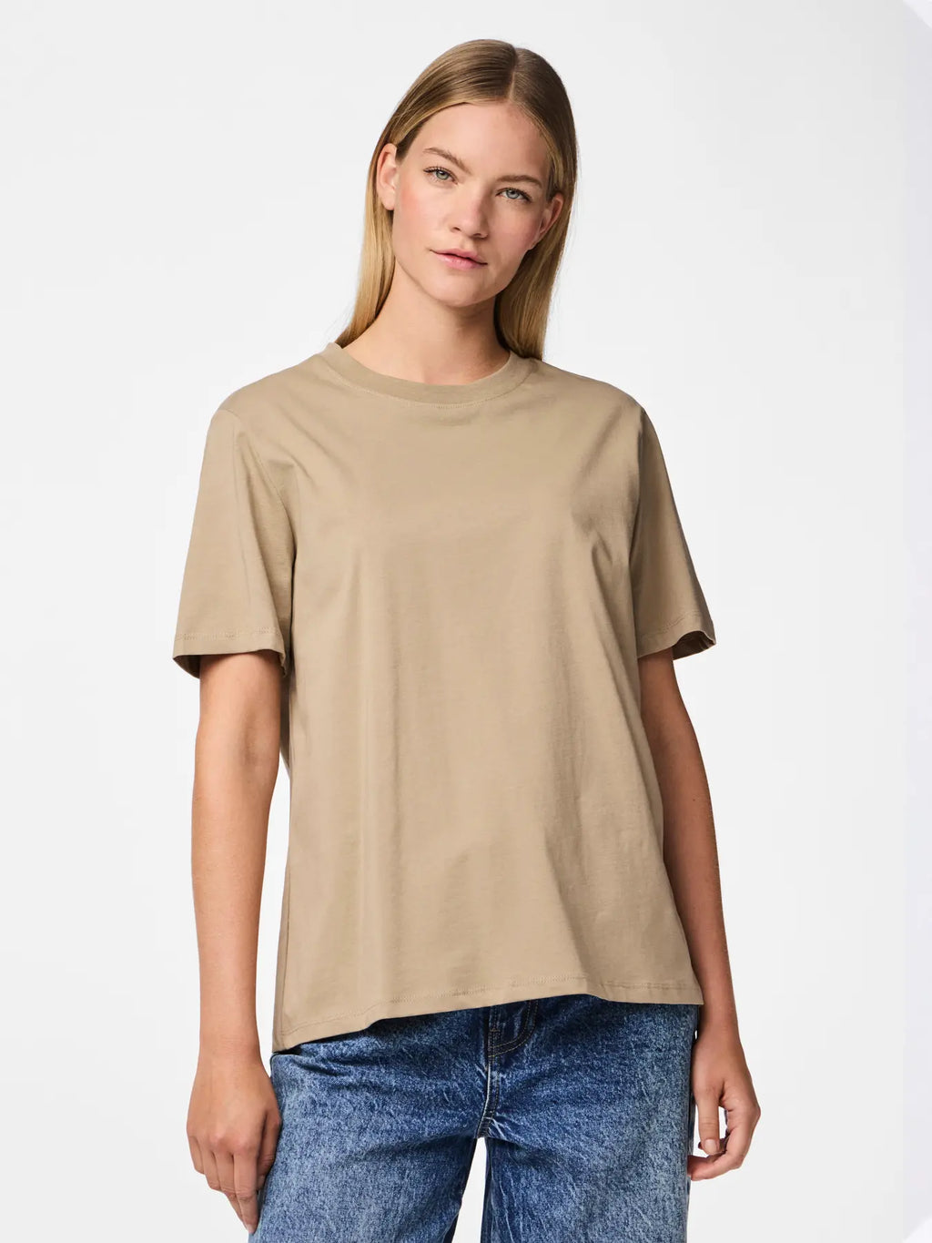 Woman wearing a beige t-shirt and blue jeans on a white background