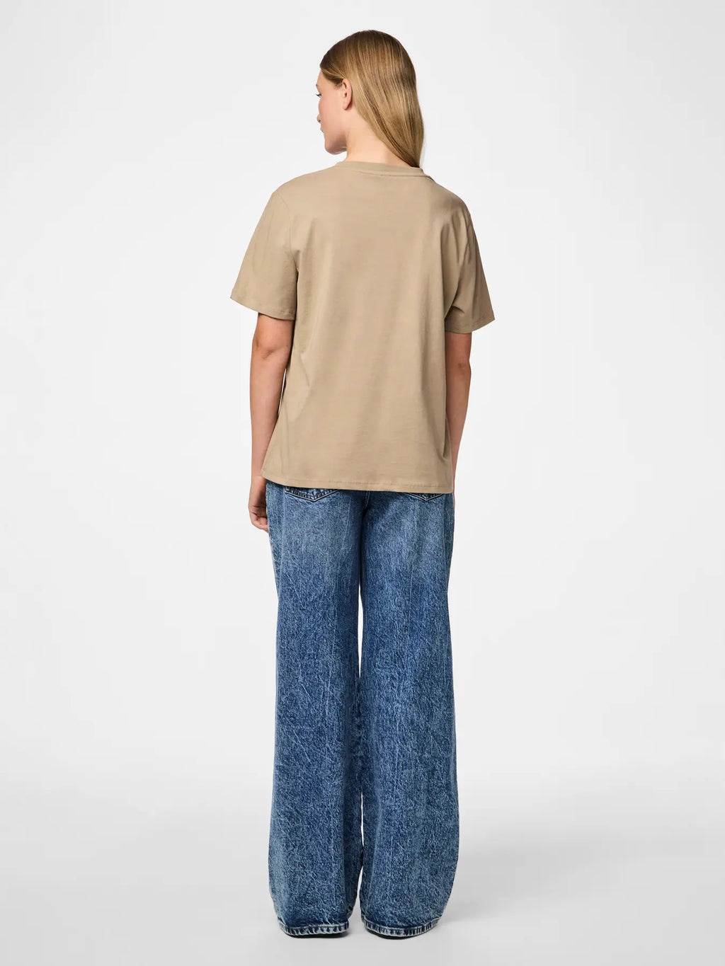 Person wearing a beige t-shirt and blue jeans on a white background