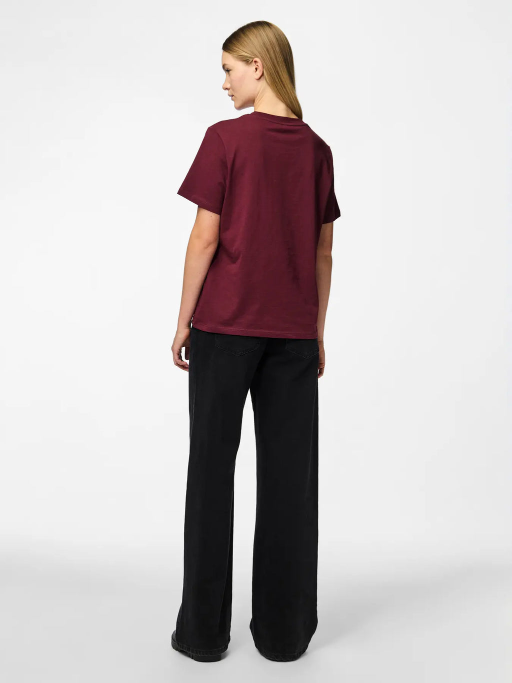 Person wearing a maroon t-shirt and black pants on a white background