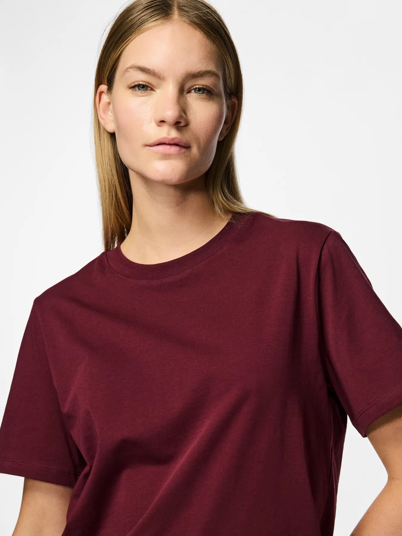 Person wearing a maroon t-shirt against a plain background