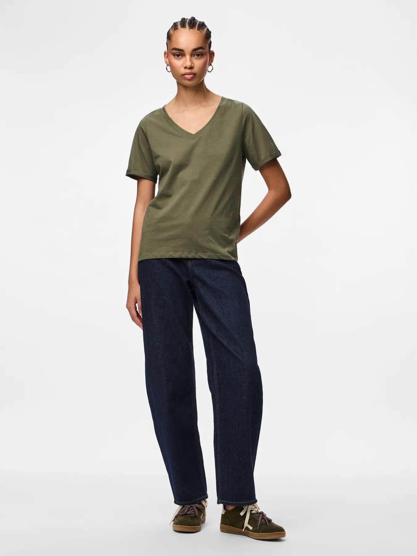 Person wearing an olive green t-shirt and navy pants on a white background