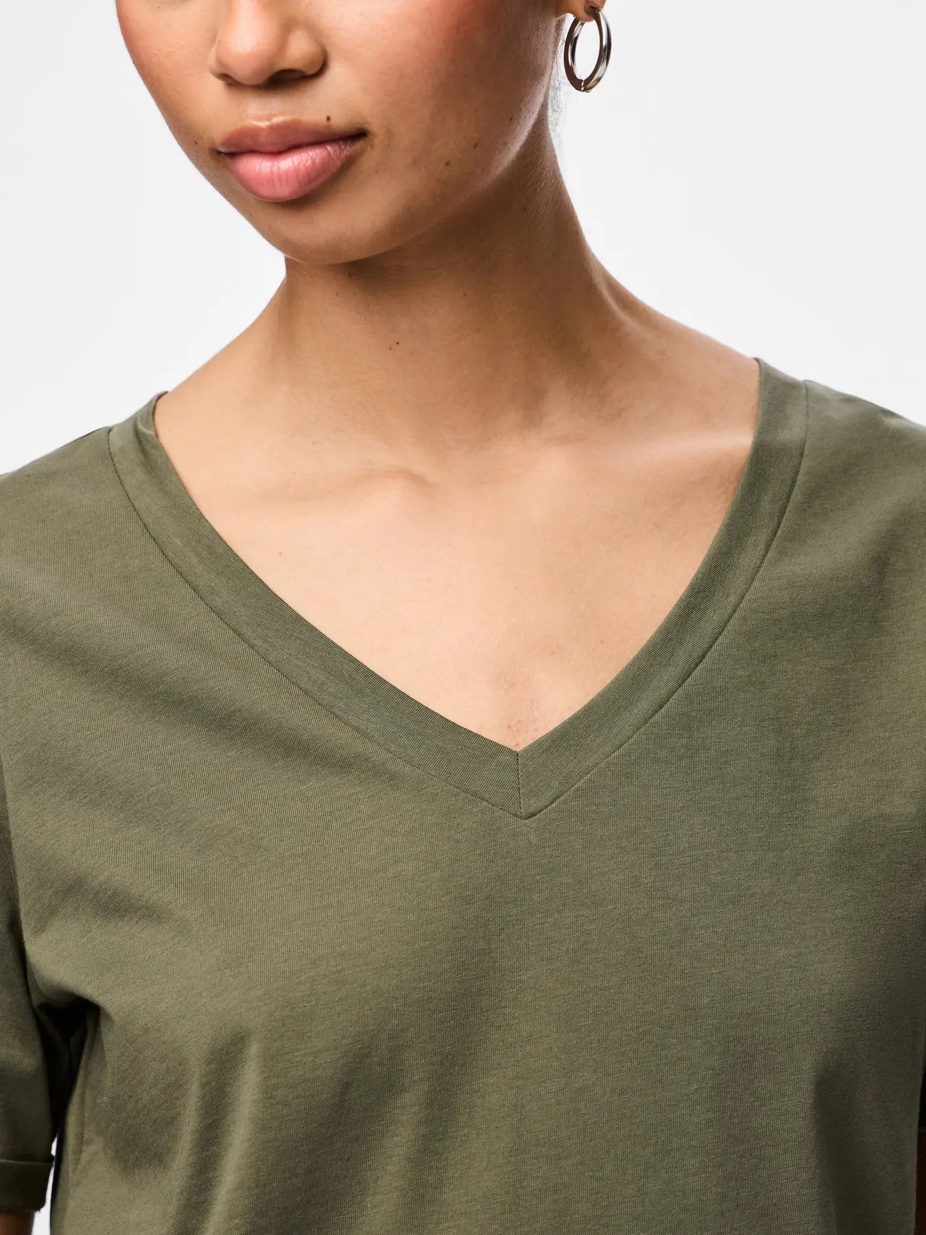 Close-up of a person wearing an olive green shirt with a plain background