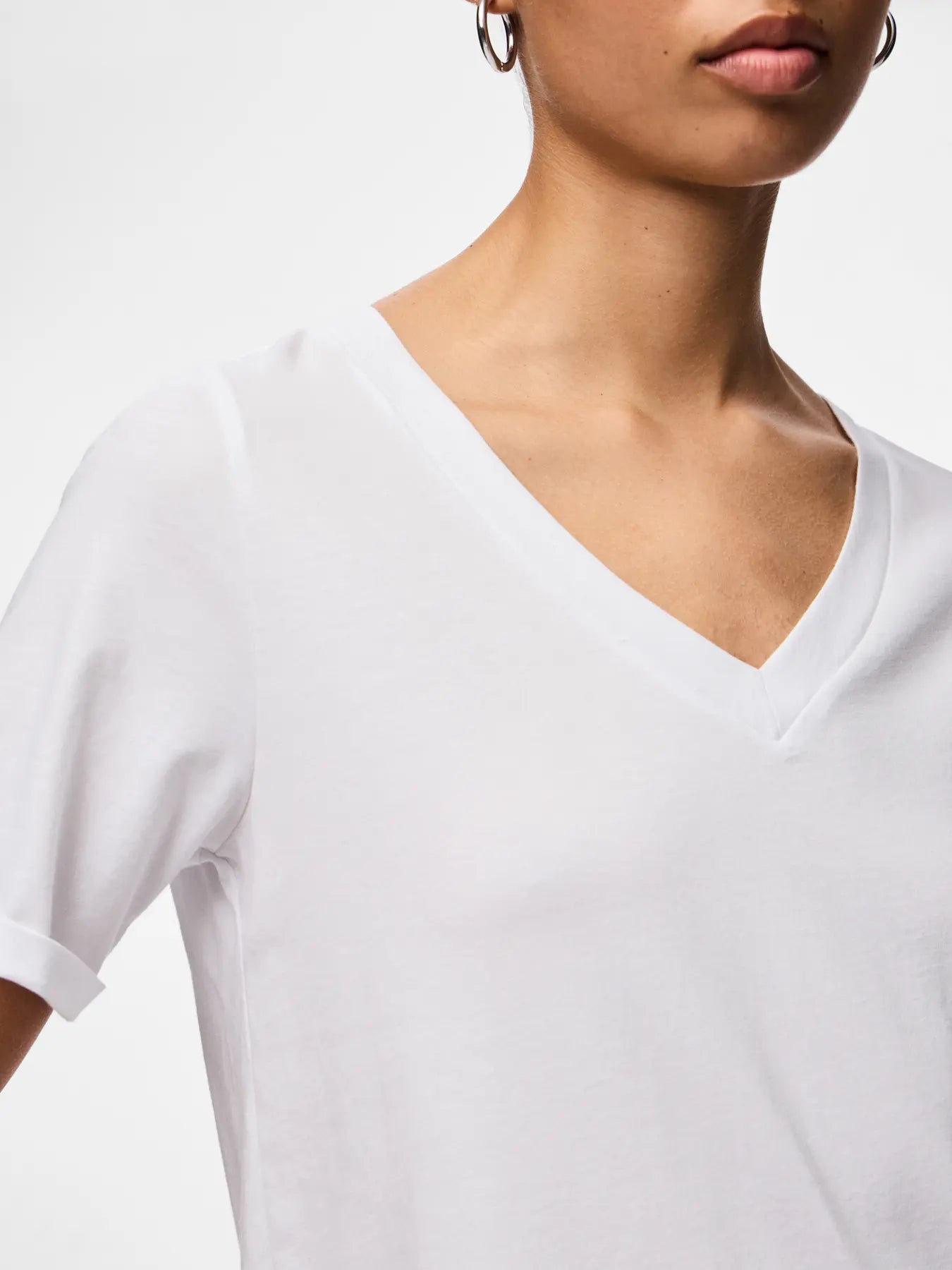 White V-neck t-shirt worn by a person on a white background