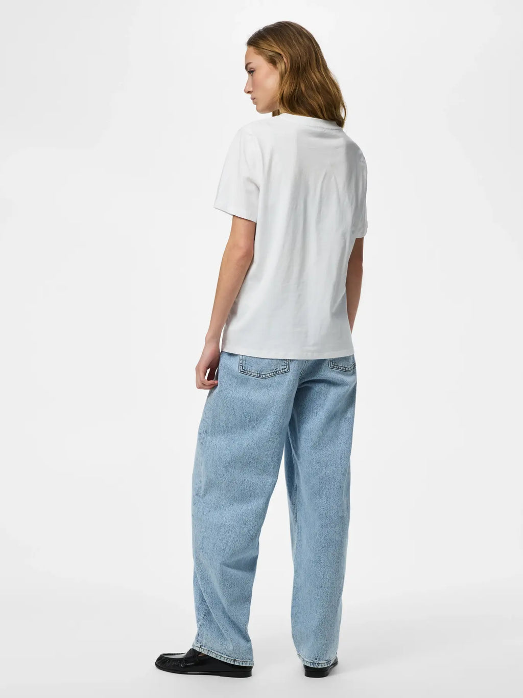 Person wearing a white t-shirt and light blue jeans on a white background