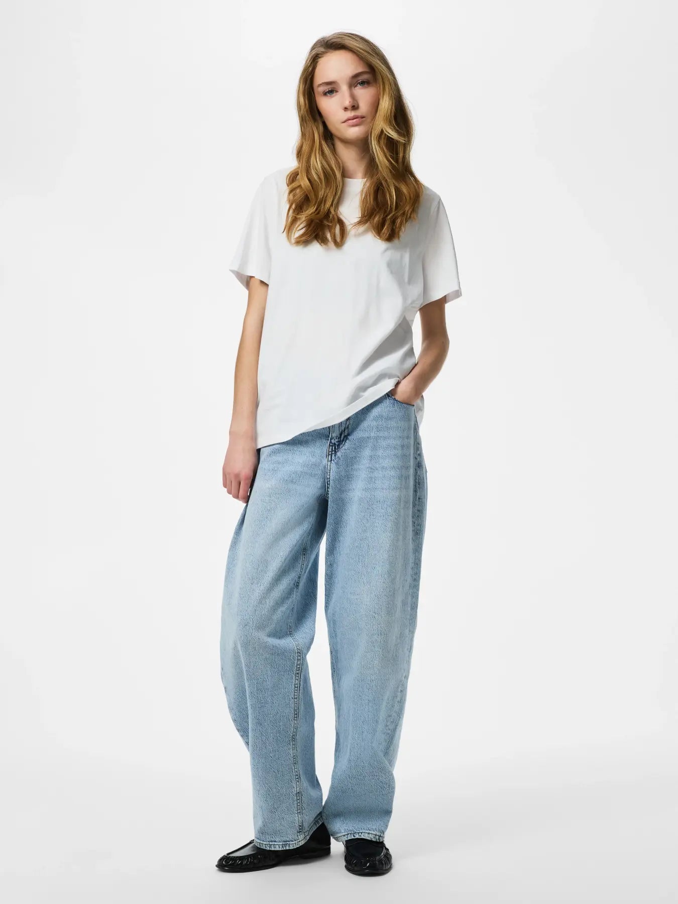 Woman wearing a white t-shirt and light blue jeans on a white background