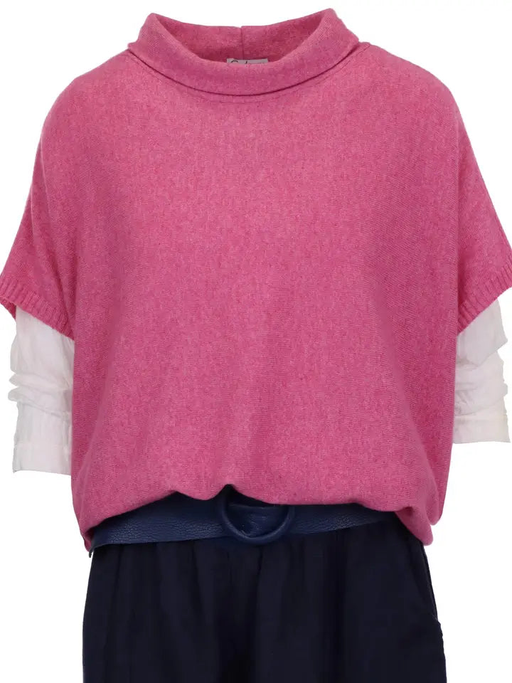 Pink sweater over a white shirt with navy pants on a white background