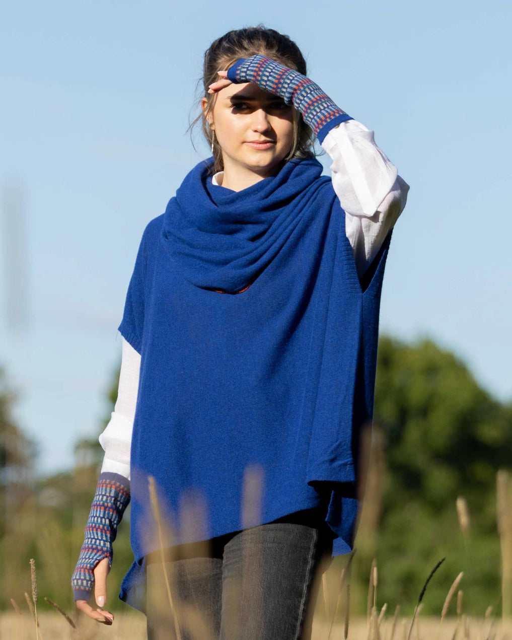 Woman wearing a blue poncho and colorful gloves in an outdoor setting