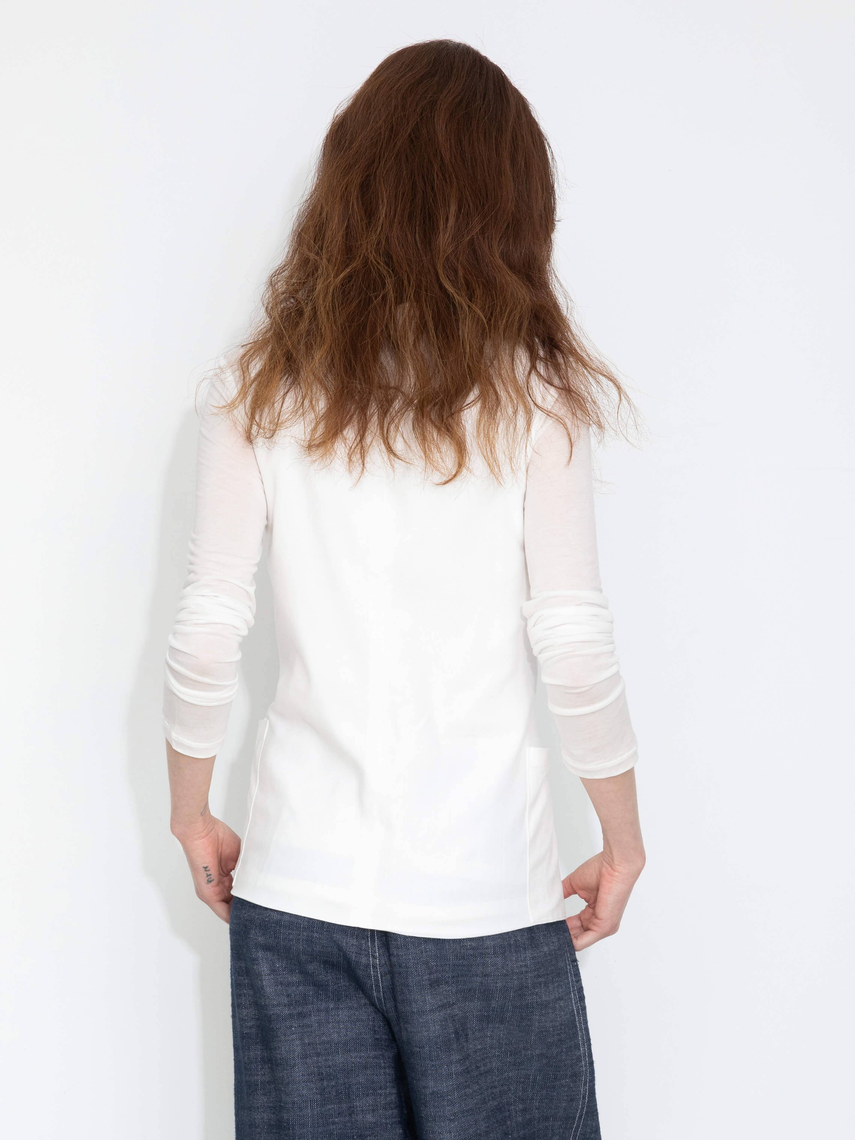 Person wearing a white long-sleeve shirt and dark pants against a white background