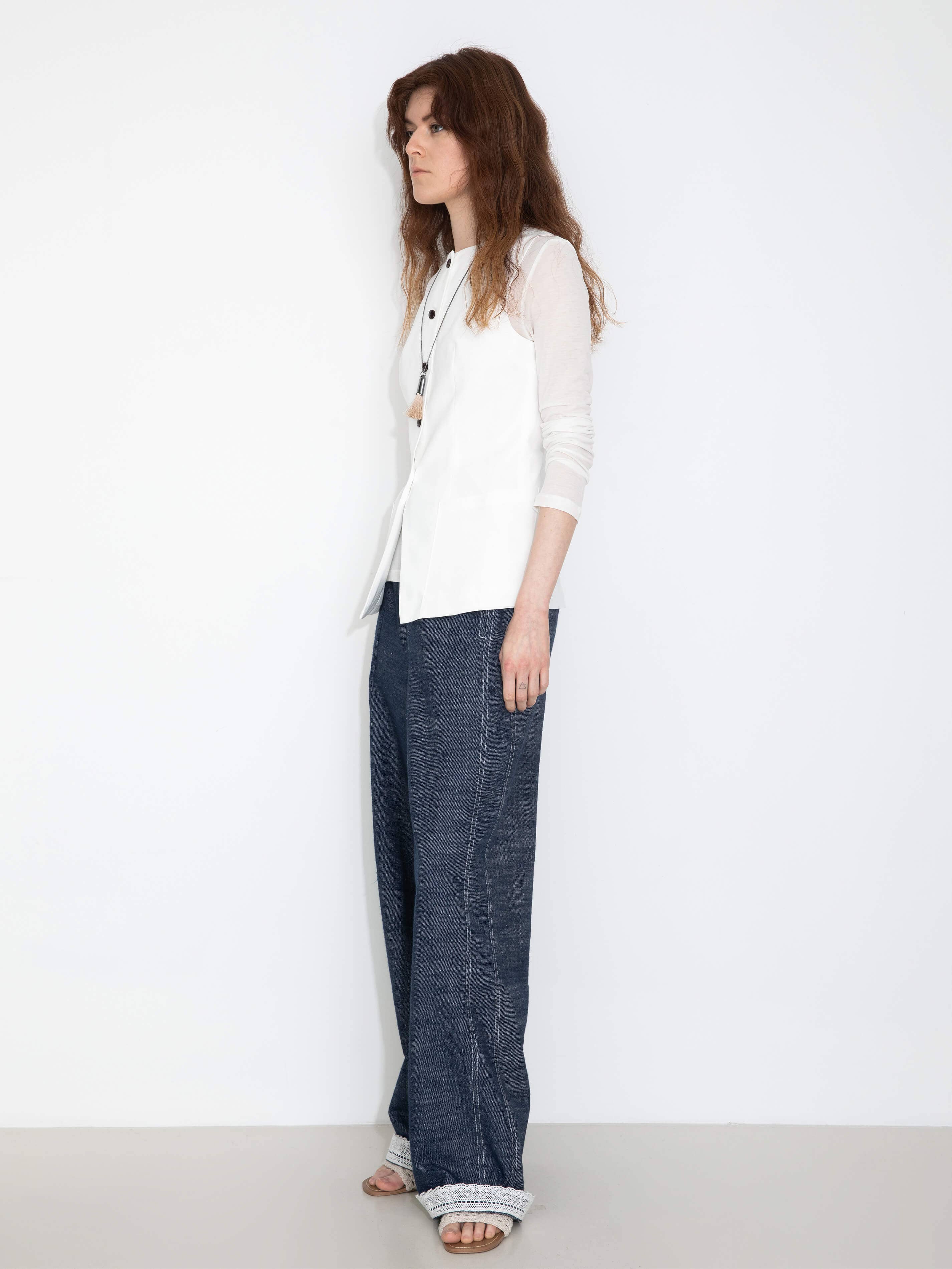Woman wearing a white blouse and blue pants on a white background
