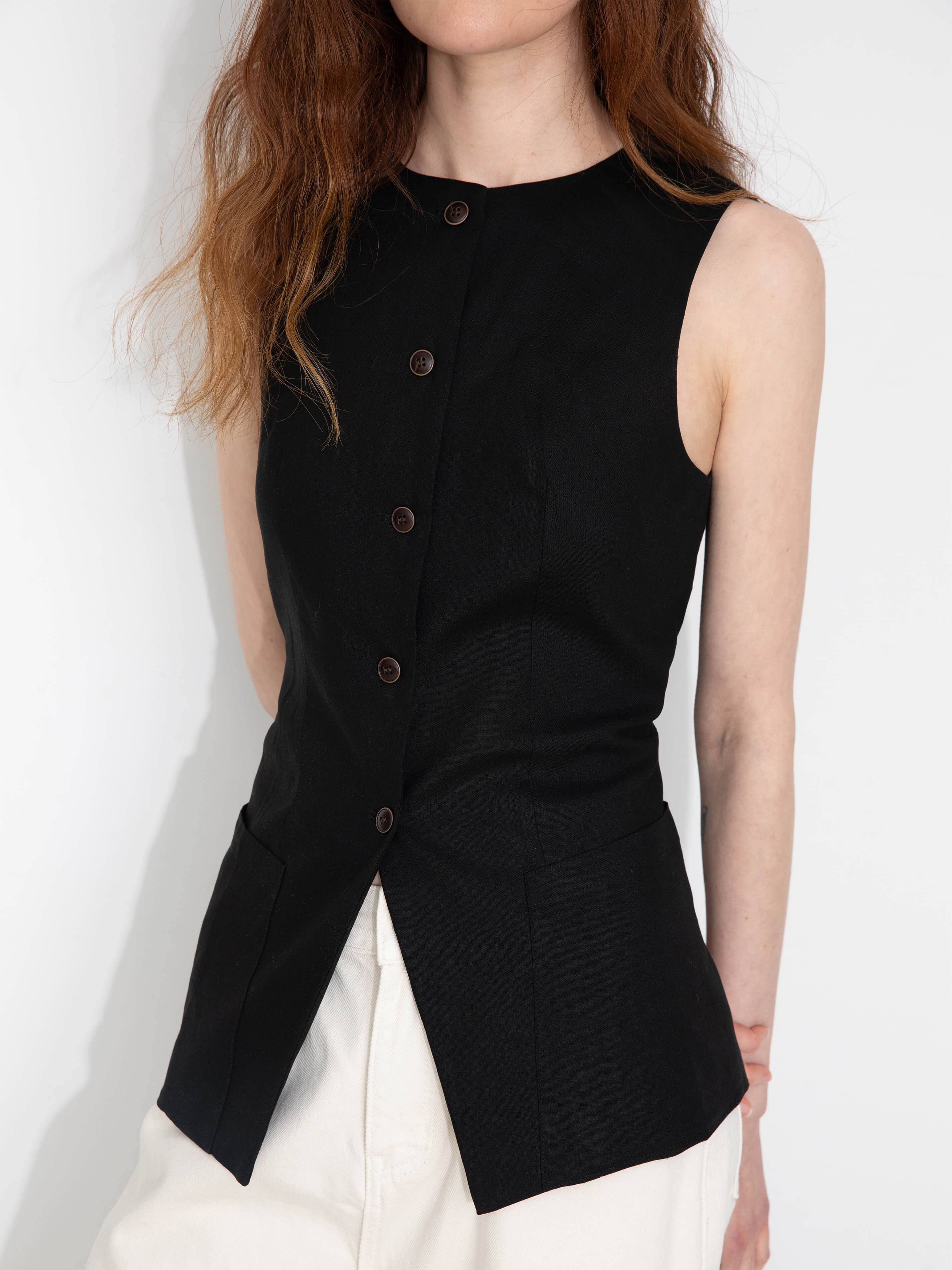 Black sleeveless button-up top worn by a person on a white background
