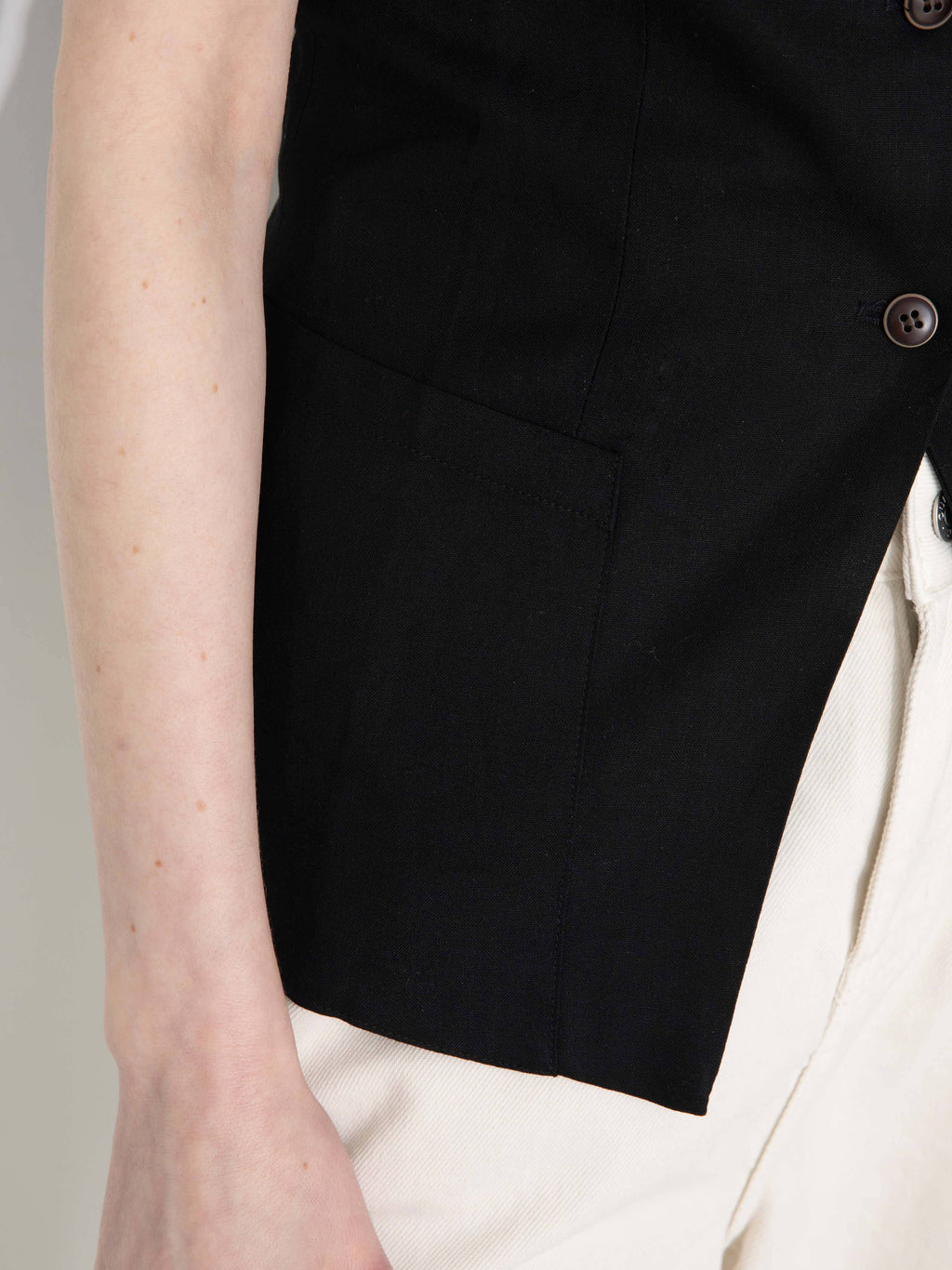 Black vest worn over a white shirt on a neutral background