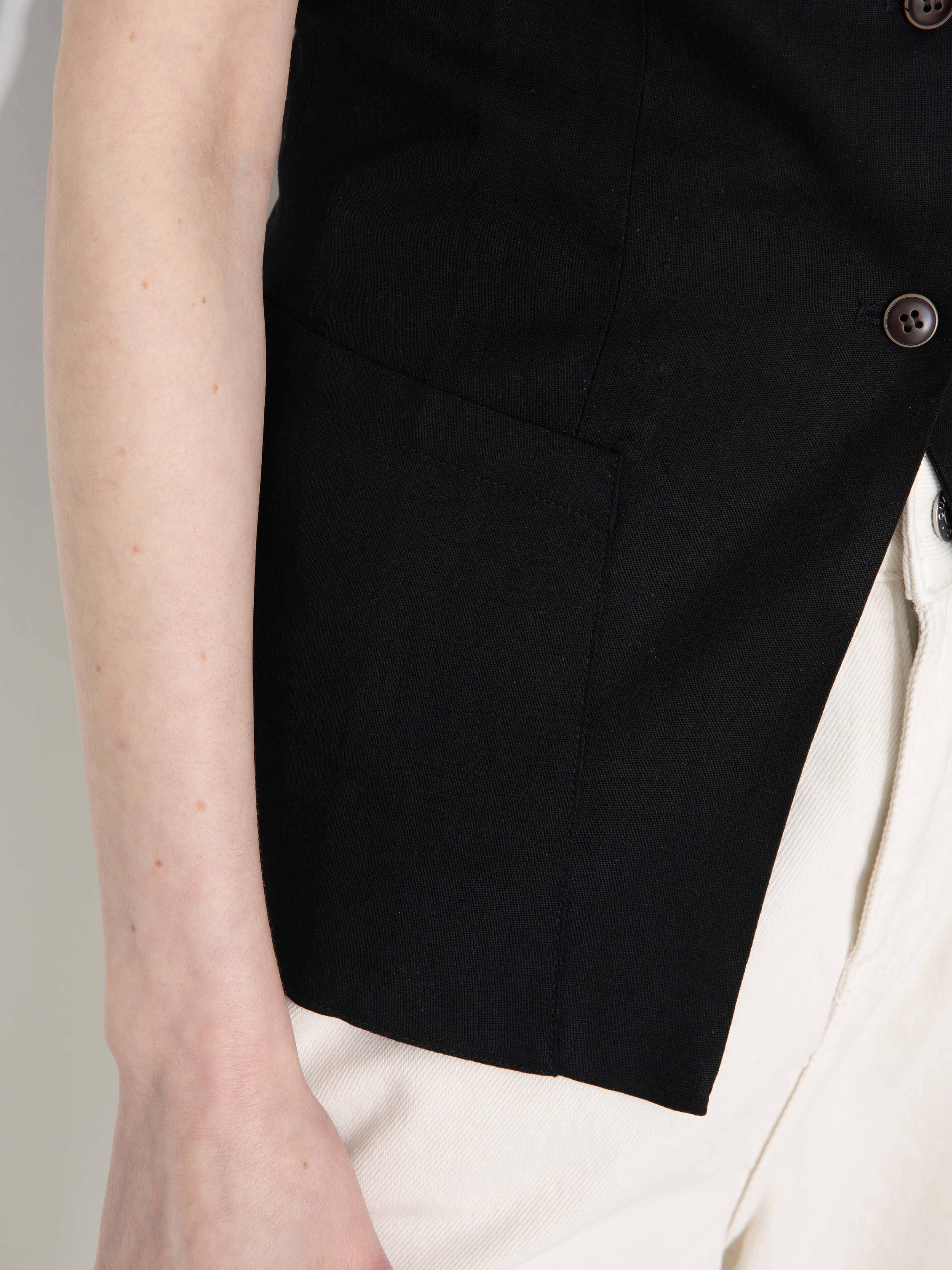 Black vest worn over a white shirt on a neutral background