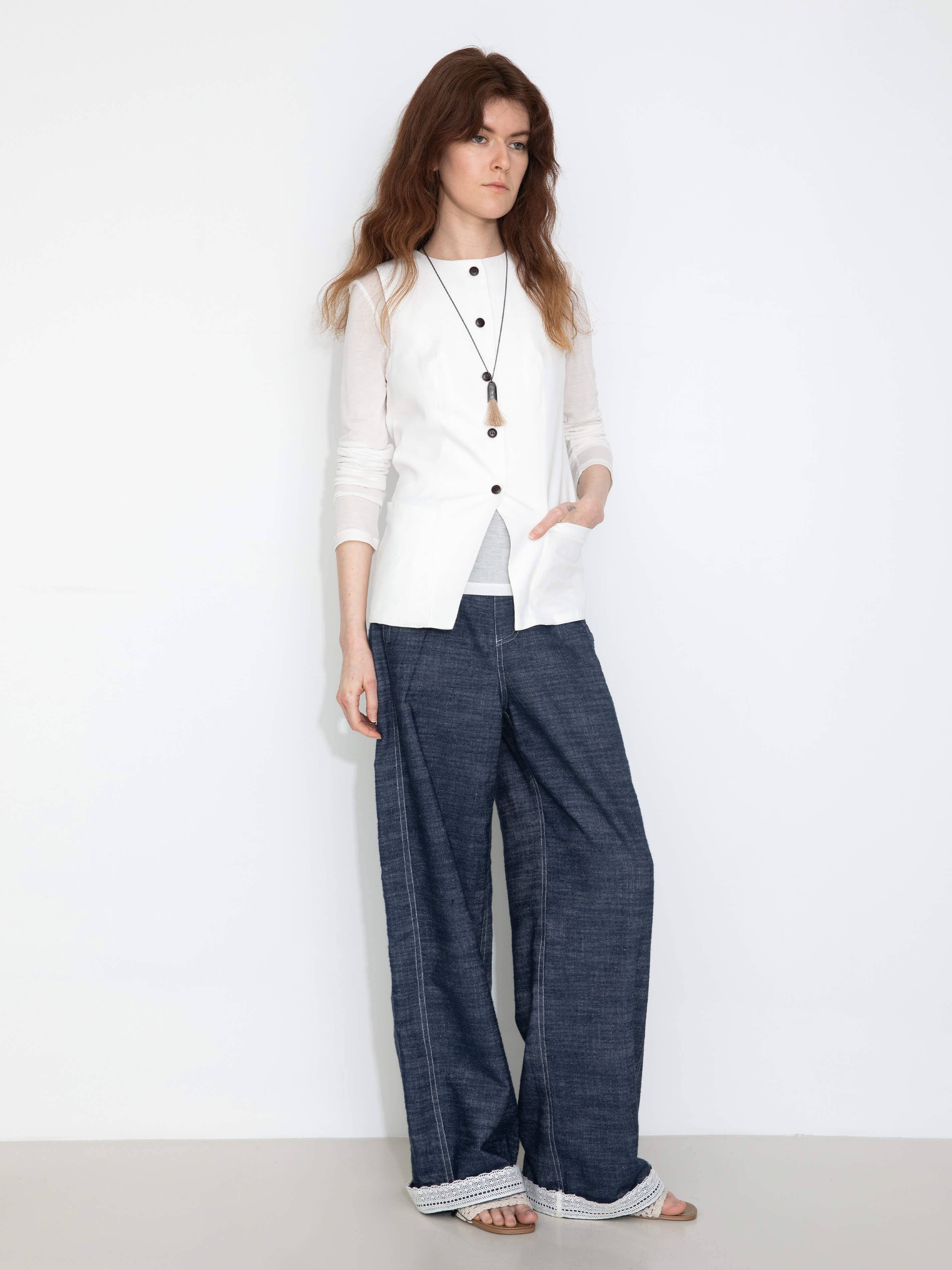 Woman wearing a white blouse and blue pants on a white background