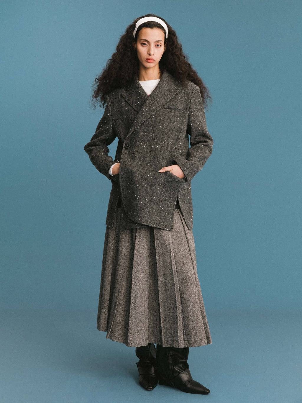 Woman wearing a long gray coat against a blue background